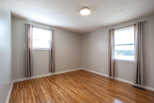 spare room with light wood-style floors, baseboards, and visible vents