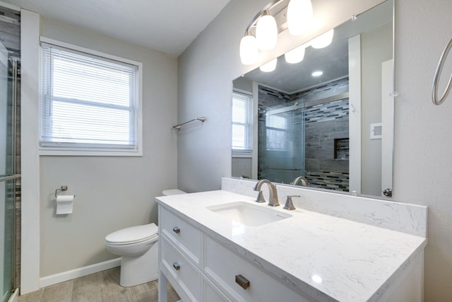 full bath featuring toilet, vanity, a shower stall, wood finished floors, and baseboards