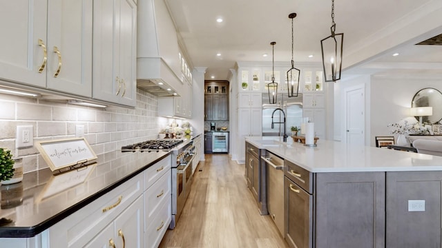 kitchen with stainless steel appliances, a spacious island, backsplash, light wood-style flooring, and a sink