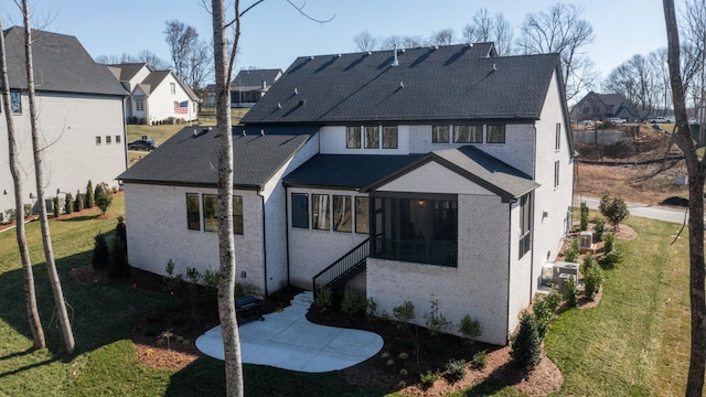 rear view of house with cooling unit, brick siding, and a lawn