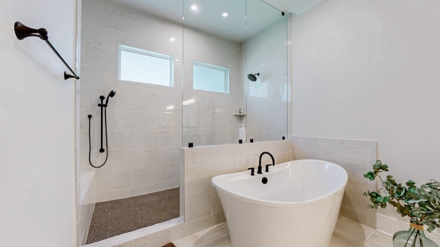 full bathroom featuring a soaking tub, a walk in shower, and tile walls