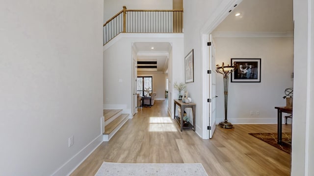 entryway featuring ornamental molding, light wood finished floors, and baseboards