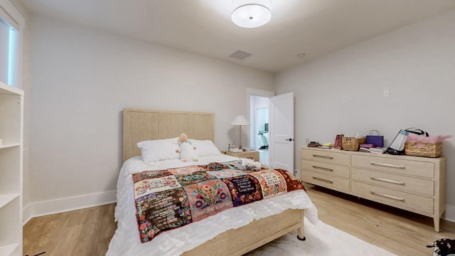 bedroom featuring light wood-style floors, visible vents, and baseboards