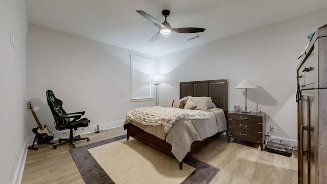 bedroom with visible vents, a ceiling fan, light wood-style flooring, and baseboards