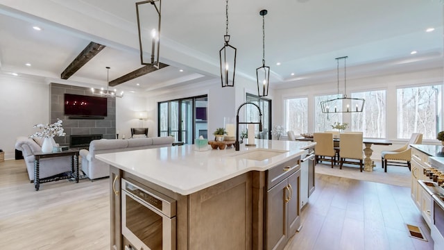 kitchen with light wood-style flooring, open floor plan, light countertops, a fireplace, and a sink