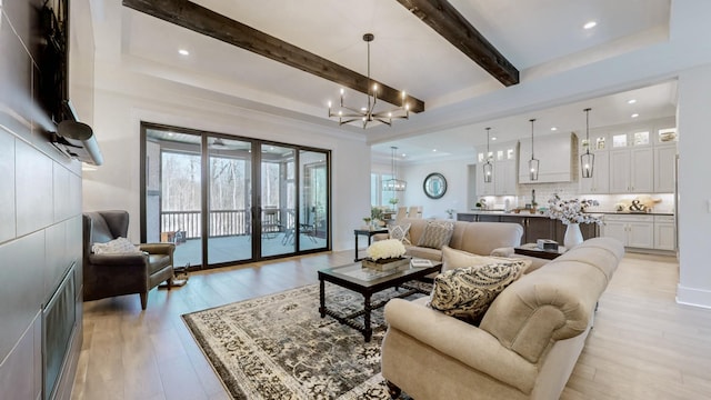 living area with recessed lighting, beamed ceiling, light wood-type flooring, and an inviting chandelier