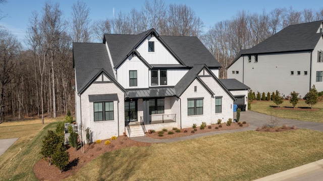 modern farmhouse style home with metal roof, brick siding, board and batten siding, a front lawn, and a standing seam roof