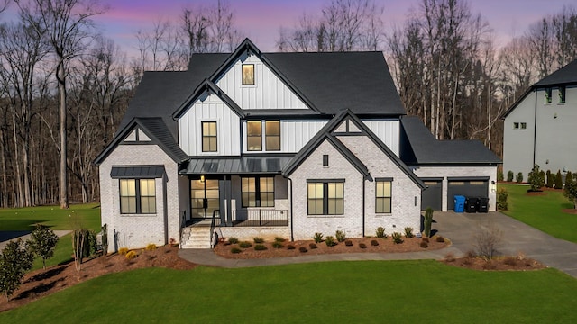 modern inspired farmhouse with brick siding, a yard, covered porch, concrete driveway, and a garage