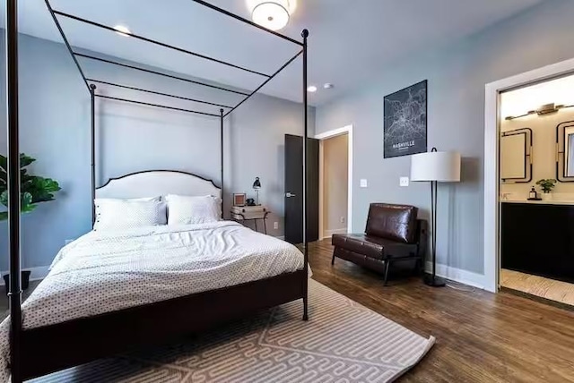 bedroom with connected bathroom, baseboards, and wood finished floors