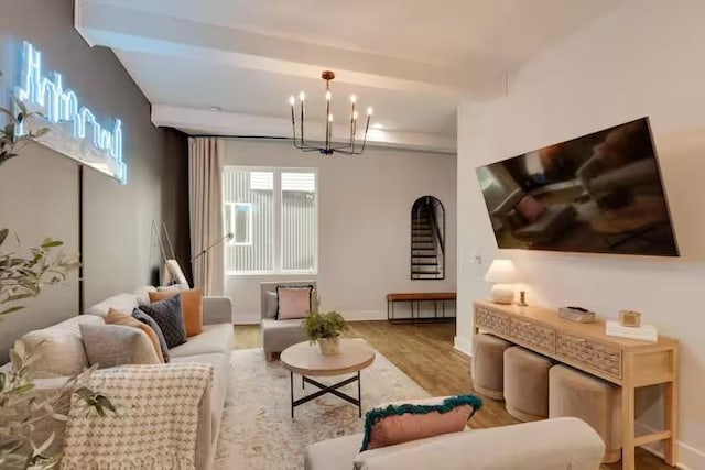 living area featuring baseboards, a chandelier, wood finished floors, and beamed ceiling