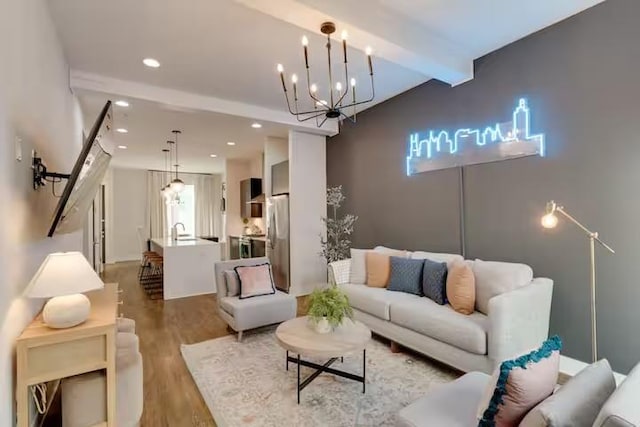 living room with a notable chandelier, beamed ceiling, wood finished floors, and recessed lighting