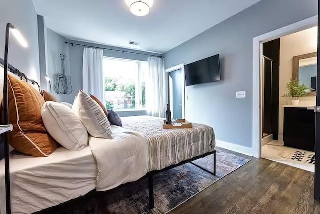 bedroom featuring dark wood-type flooring, connected bathroom, visible vents, and baseboards