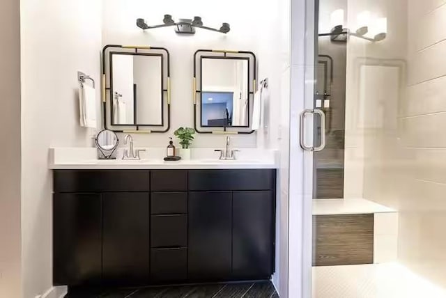 bathroom featuring double vanity, a stall shower, and a sink