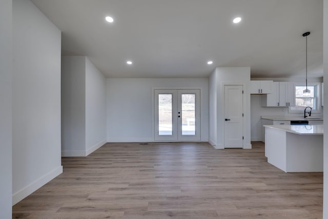 kitchen featuring pendant lighting, french doors, light countertops, light wood-style floors, and white cabinets