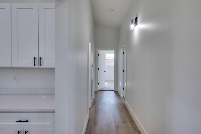 corridor featuring light wood-style flooring and baseboards