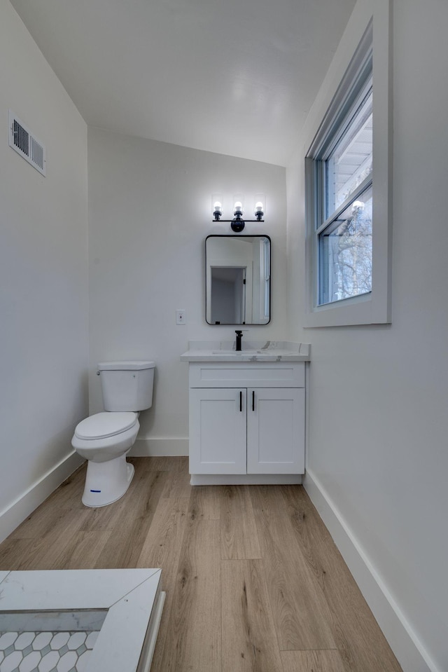 bathroom featuring visible vents, vanity, baseboards, and wood finished floors