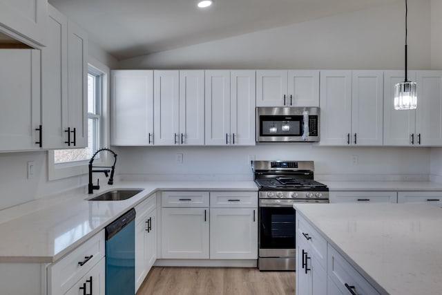 kitchen with vaulted ceiling, white cabinetry, stainless steel appliances, and a sink