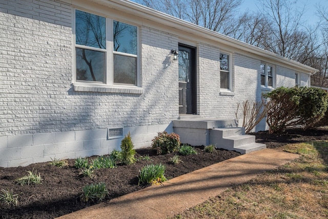 view of exterior entry featuring brick siding and crawl space