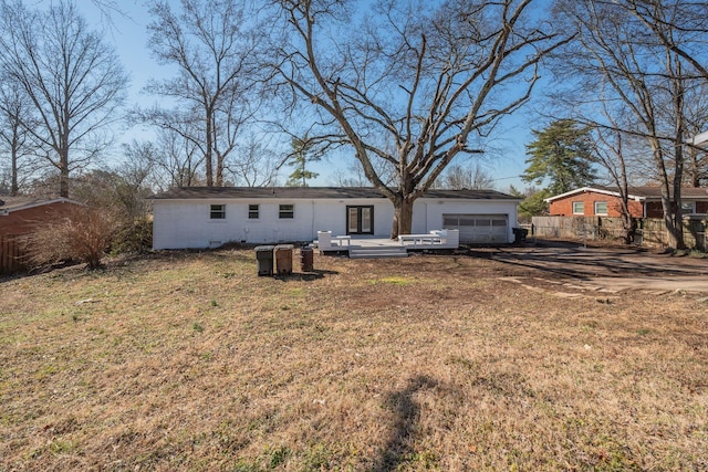 rear view of property with a garage, a yard, a wooden deck, and fence