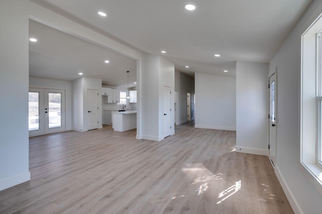 unfurnished living room featuring recessed lighting, french doors, and light wood-style flooring