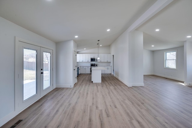 kitchen with a center island, open floor plan, white cabinetry, and stainless steel microwave