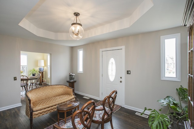 entryway featuring dark wood-style floors, a tray ceiling, and baseboards