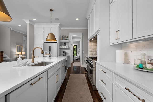 kitchen featuring appliances with stainless steel finishes, light countertops, white cabinetry, pendant lighting, and a sink