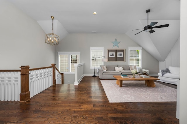 living room with baseboards, vaulted ceiling, dark wood-type flooring, and ceiling fan with notable chandelier