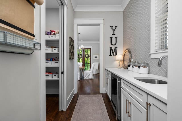 kitchen featuring ornamental molding, white cabinets, light countertops, and a sink