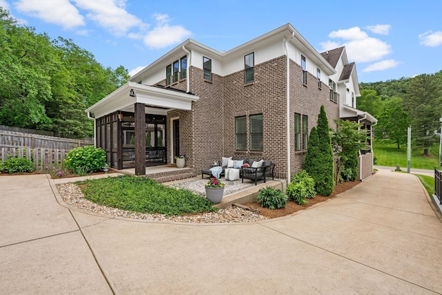 view of front of property with brick siding, fence, and a sunroom