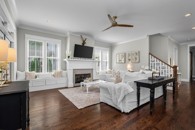 living room with dark wood-style flooring, recessed lighting, ornamental molding, a glass covered fireplace, and a ceiling fan