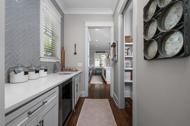 bar featuring decorative backsplash, dark wood finished floors, wine cooler, crown molding, and a sink