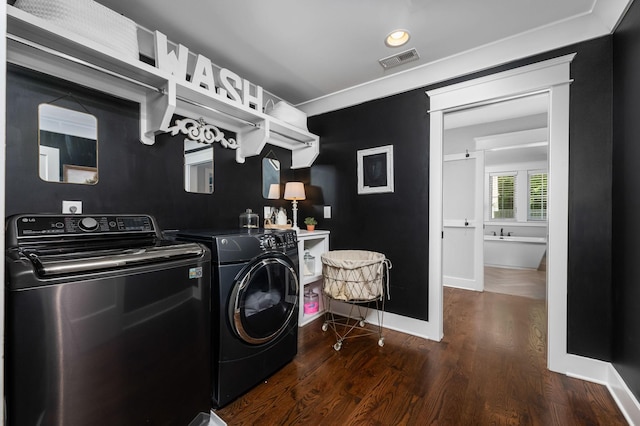 clothes washing area with laundry area, dark wood-type flooring, visible vents, baseboards, and washer and clothes dryer