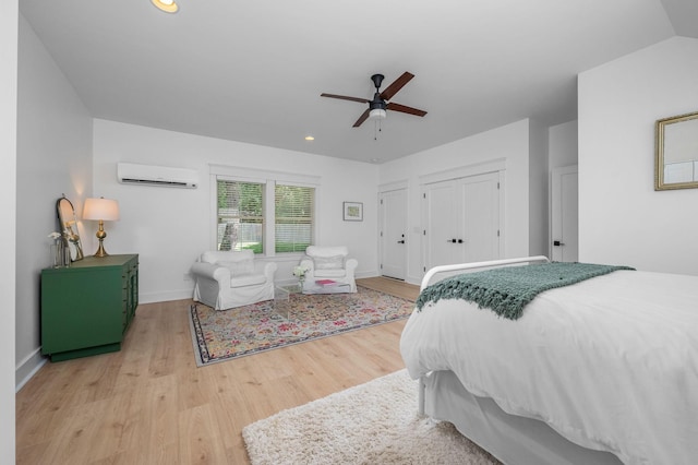 bedroom featuring a wall unit AC, light wood finished floors, baseboards, and a ceiling fan