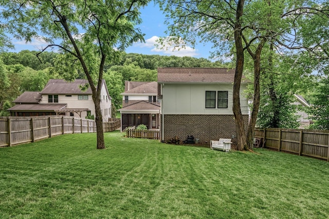 back of property with brick siding, a lawn, and a fenced backyard