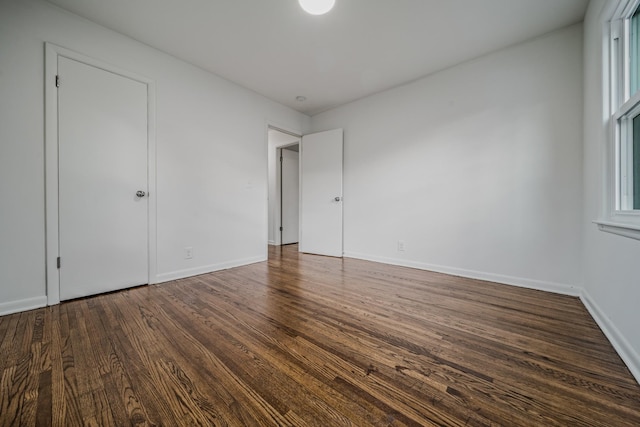 unfurnished bedroom featuring baseboards and dark wood-type flooring