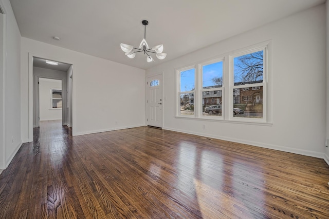 interior space featuring dark wood-style floors, baseboards, and an inviting chandelier