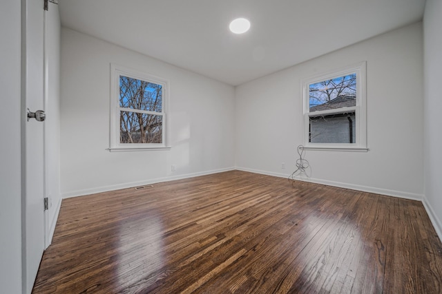 unfurnished bedroom featuring dark wood-style floors, visible vents, and baseboards