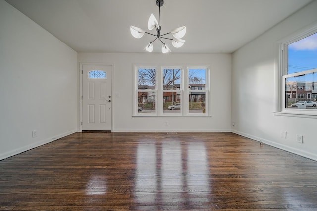 entrance foyer with dark wood-type flooring, a wealth of natural light, baseboards, and an inviting chandelier