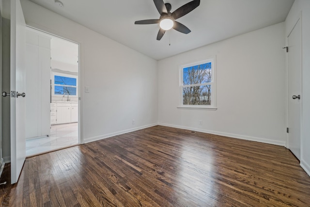 unfurnished bedroom with a sink, ceiling fan, baseboards, and dark wood-type flooring