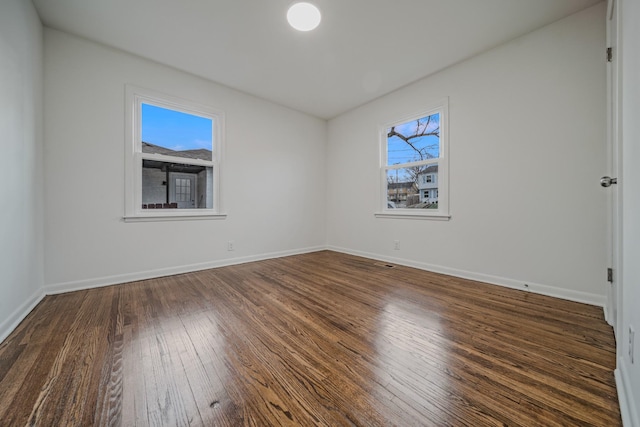 unfurnished room with dark wood-type flooring and baseboards