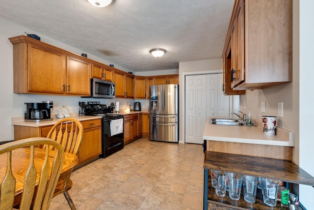 kitchen with appliances with stainless steel finishes, light countertops, brown cabinets, and a sink