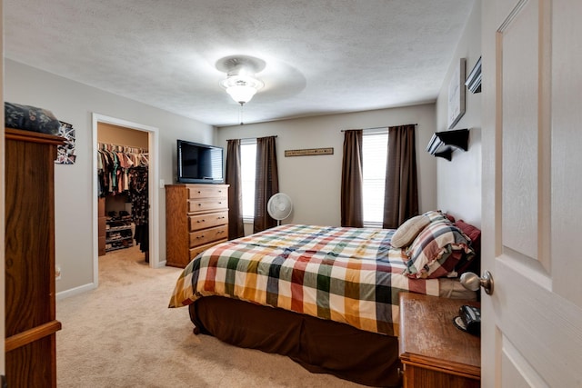 bedroom featuring a closet, light carpet, a spacious closet, and a textured ceiling