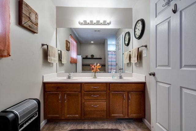 bathroom with curtained shower, a sink, heating unit, and double vanity