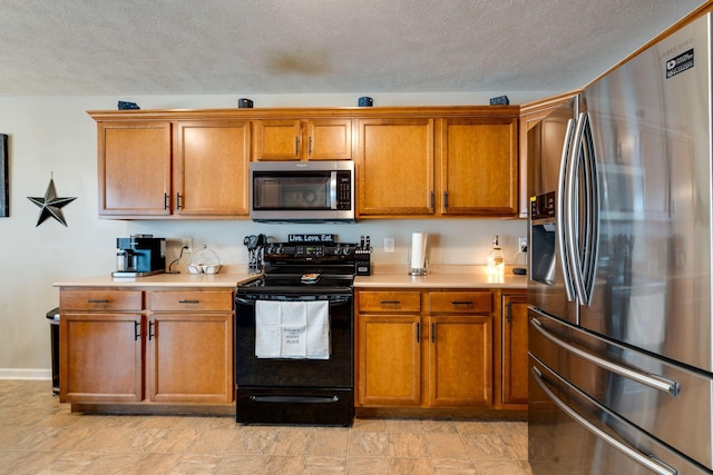 kitchen featuring a textured ceiling, stainless steel appliances, light countertops, and brown cabinets