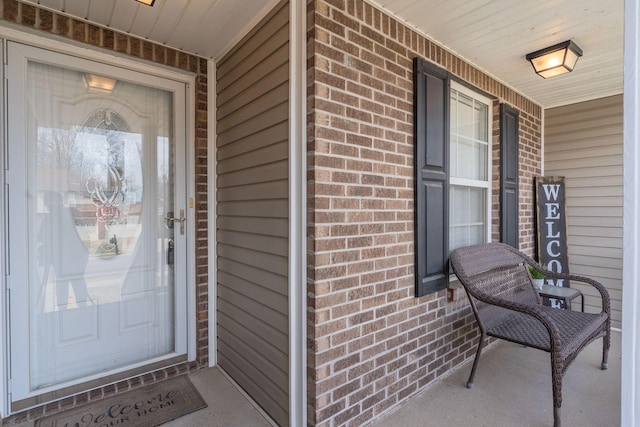 entrance to property featuring a porch and brick siding