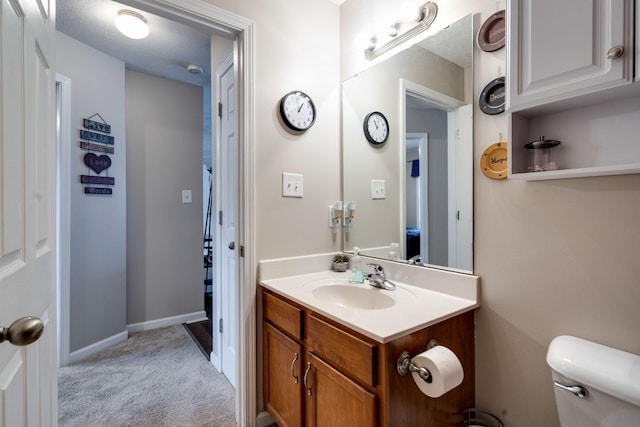 bathroom featuring toilet, baseboards, a textured ceiling, and vanity