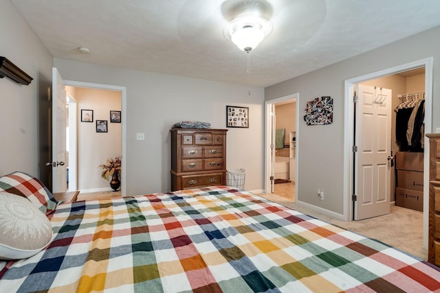 bedroom with light carpet, a spacious closet, a closet, and baseboards