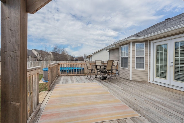 wooden terrace with fence, outdoor dining area, and french doors