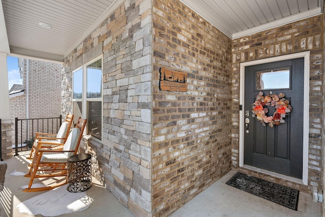 property entrance with stone siding, covered porch, and brick siding